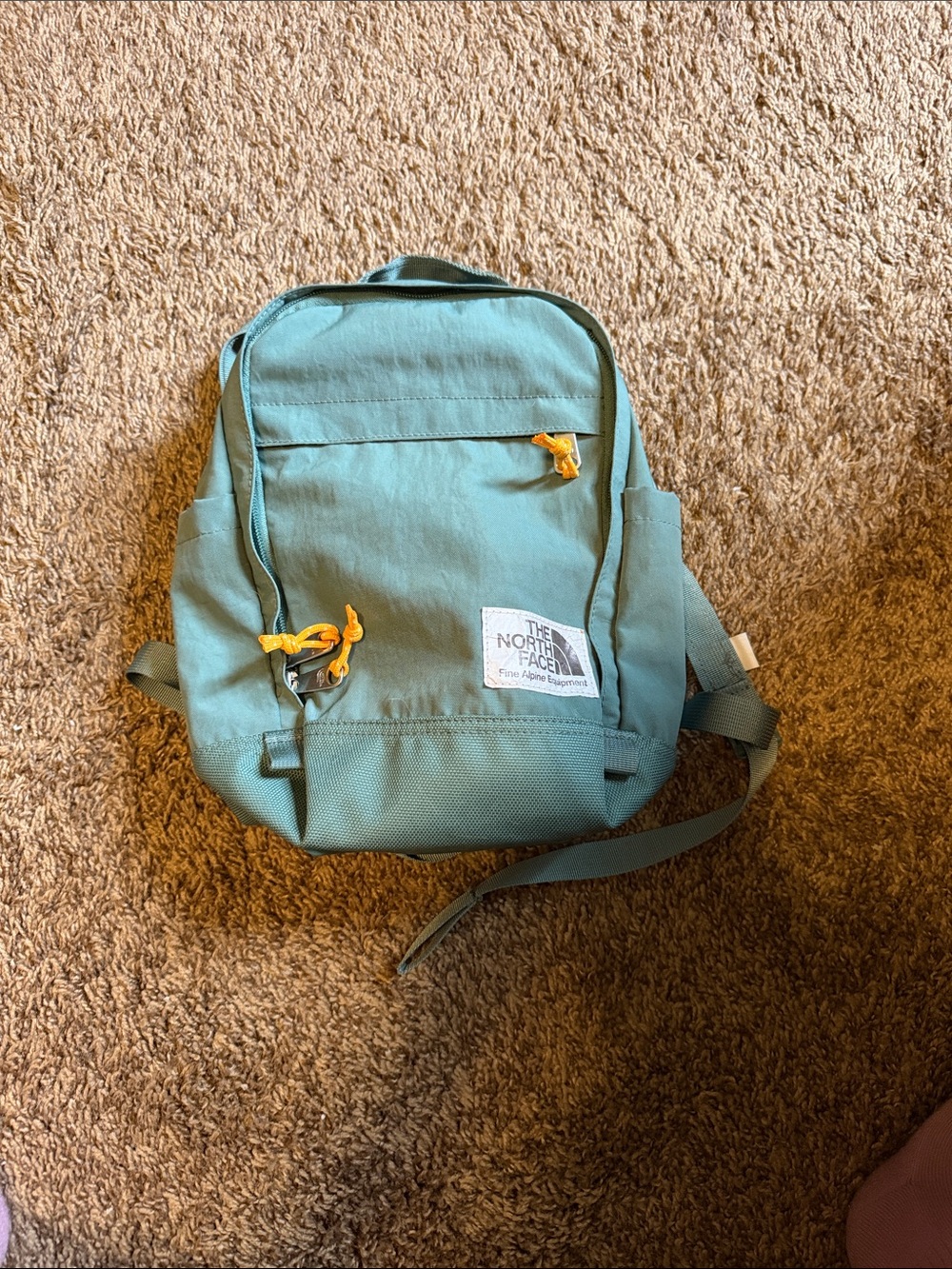 The North Face teal mini backpack with yellow accents